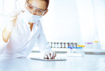 Female laboratory assistant analyzing test tube with blue liquid. Medicine, health care and researching concept