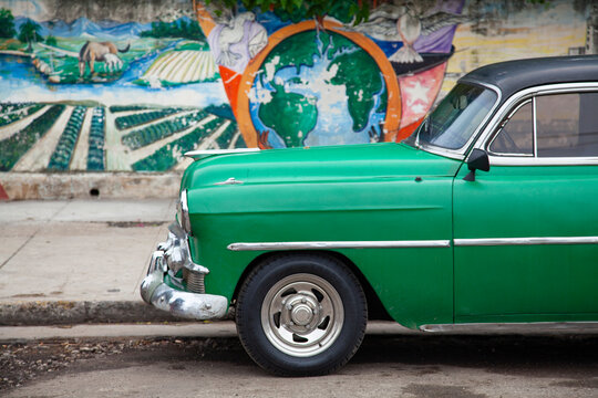 Classic old American vintage cars with a painted mural in the background, Havana Cuba