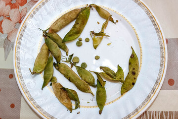 Dried green pea pods on a plate.