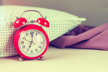 Red alarm-clock in the badroom, morning time, toned.	