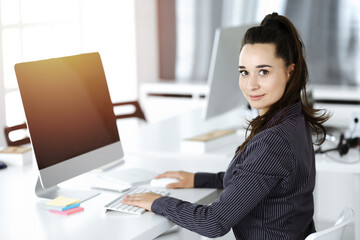 Business woman using computer at workplace in sunny office. Working for pleasure and success