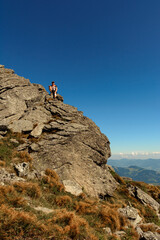A man stands on the edge of a stone on one of the peaks of the Ukrainian Carpathians, the Montenegrin ridge, picturesque mountains on the trampled trails of the Carpathians.
