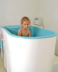 A little girl takes the procedure in a hot tub. Hydrotherapy