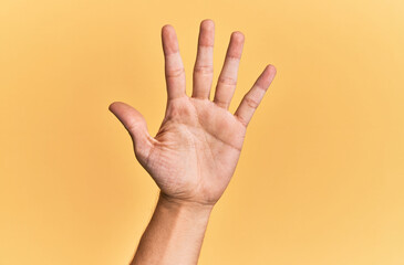 Arm and hand of caucasian man over yellow isolated background counting number 5 showing five fingers