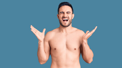 Young handsome man wearing swimwear celebrating mad and crazy for success with arms raised and...