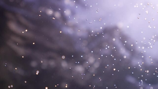 air bubbles underwater in blue water moving strange some in focus some out of focus making nive background shapes with sun rays and sun shine