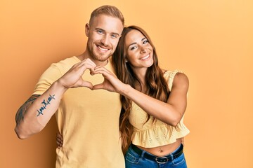 Young couple of girlfriend and boyfriend hugging and standing together smiling in love doing heart symbol shape with hands. romantic concept.