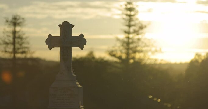 Cemetery at Sunset, grave stones and crosses from 1800-1900s. Insects flying around in the warm air. Rest in peace.