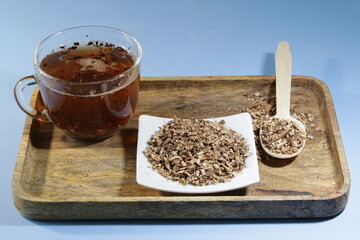 Wild chaga mushroom. A medicinal drink made from the fungus in a transparent cup on a wooden tray. Finely chopped chaga mushroom into pieces.