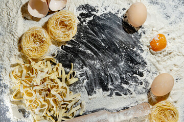 Pasta with ingredients - flour, eggs and different tools for cooking on black table. Free space for text . Top view.