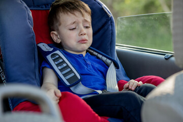 Little boy buckled up with seatbelt inside the car. Vehicle and transportation concept.