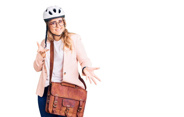 Young caucasian woman wearing bike helmet and leather bag clueless and confused expression with arms and hands raised. doubt concept.