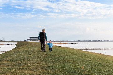 Man with toddler walking on dyke
