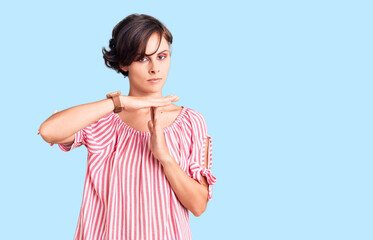 Beautiful young woman with short hair wearing casual summer clothes doing time out gesture with hands, frustrated and serious face