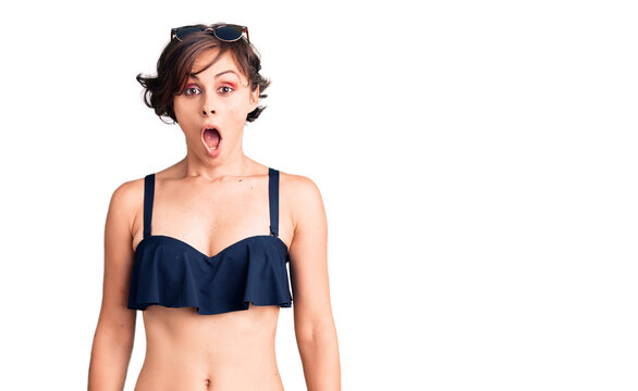 Beautiful young woman with short hair wearing bikini scared and amazed with open mouth for surprise, disbelief face