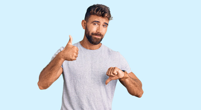 Young hispanic man wearing casual clothes doing thumbs up and down, disagreement and agreement expression. crazy conflict
