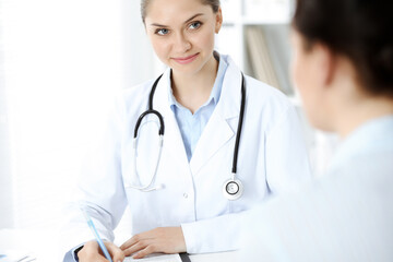 Friendly smiling doctor and patient sitting at the table. Very good news and high level medical service concept