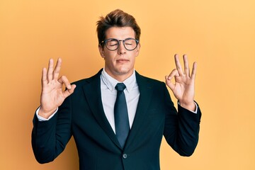 Handsome caucasian man wearing business suit and tie relax and smiling with eyes closed doing meditation gesture with fingers. yoga concept.