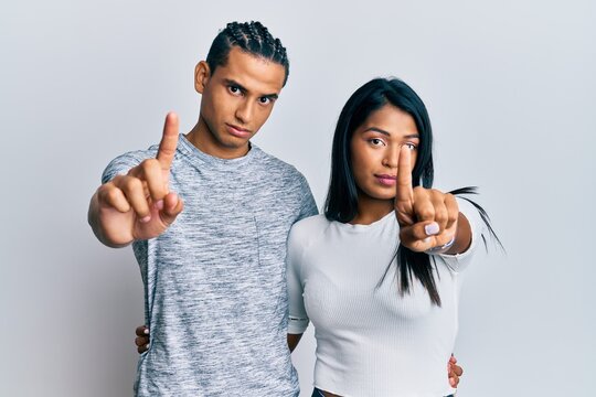 Young latin couple wearing casual clothes pointing with finger up and angry expression, showing no gesture