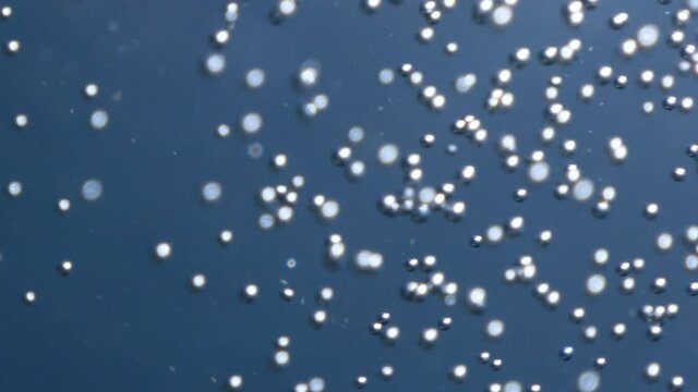 air bubbles underwater in blue water moving strange some in focus some out of focus making nive background shapes with sun rays and sun shine