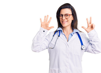 Young beautiful woman wearing doctor stethoscope and glasses showing and pointing up with fingers number eight while smiling confident and happy.