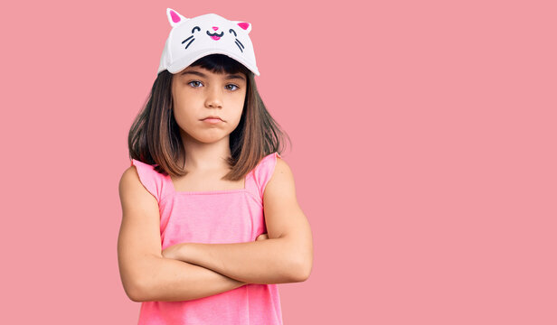 Young little girl with bang wearing funny kitty cap skeptic and nervous, disapproving expression on face with crossed arms. negative person.