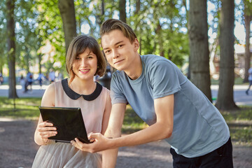 Smiling couple with tablet PC in park.