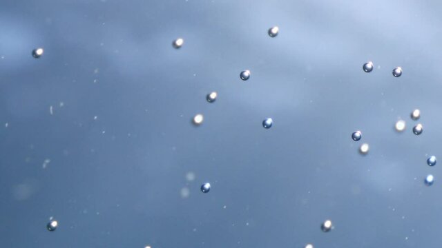 air bubbles underwater in blue water moving strange some in focus some out of focus making nive background shapes with sun rays and sun shine
