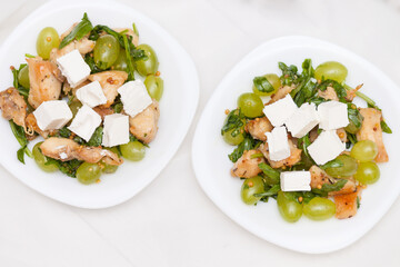 Tasty and healthy salad with feta cheese, grapes, chicken, arugula.