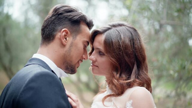 Sincere and romantic emotions of young married couple, handsome husband kissing his pretty wife while woman hugging him lovely. Tenderness and affection in bodies gestures, love between people