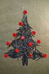 christmas tree folded from construction nails decorated red stars on kraft paper background.