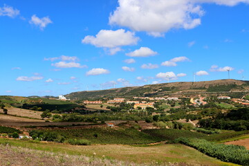 Wonderful panoramic views of the natural landscapes of Portugal. View of blue skies, high hills, wind turbines and traditional ceramic tiled roof houses