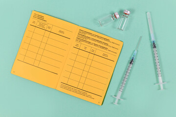 Concept for vaccination with syringes, vials and empty yellow international certificate of...