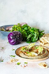 An oriental dish of baked eggplant babaganush (eggplant puree) with spices, herbs, lettuce and oriental flatbreads.