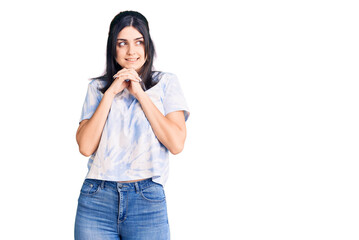 Young beautiful girl wearing casual t shirt laughing nervous and excited with hands on chin looking to the side