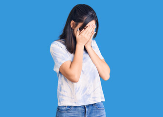 Young beautiful girl wearing casual t shirt with sad expression covering face with hands while crying. depression concept.