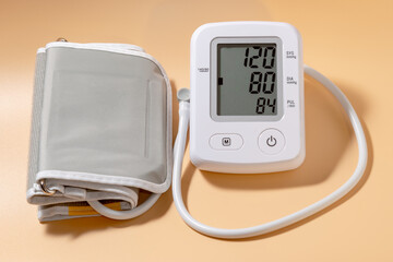 Modern white electric tonometer on a light orange background close-up with the measured pressure.