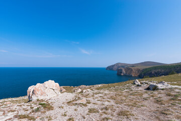 Fototapeta na wymiar Mountain landscape of Olkhon island. Blue sky over the Maloye More Strait and cape Khoboi. View from cape Sagan Khushum..