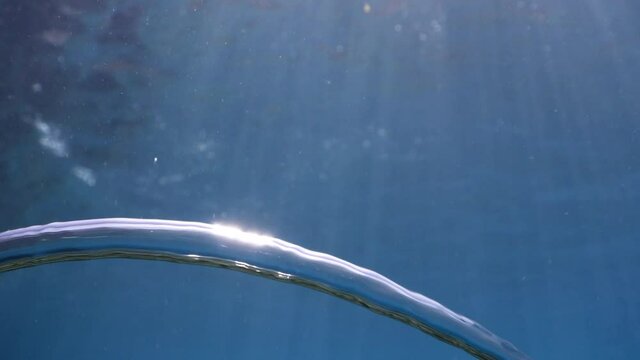 air bubbles underwater in blue water moving strange some in focus some out of focus making nive background shapes with sun rays and sun shine