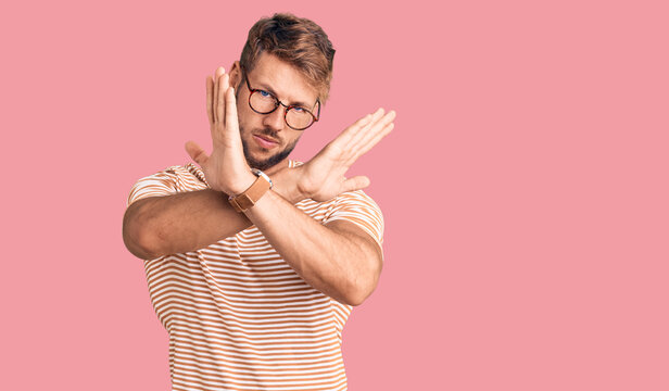 Young caucasian man wearing casual clothes and glasses rejection expression crossing arms doing negative sign, angry face
