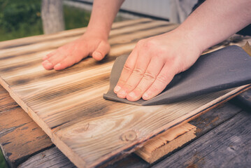 sanding a wooden surface/man's hand processes a wooden surface with sandpaper