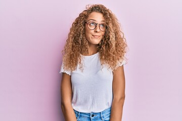 Beautiful caucasian teenager girl wearing white t-shirt over pink background smiling looking to the side and staring away thinking.