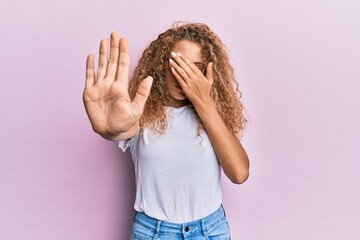 Beautiful caucasian teenager girl wearing white t-shirt over pink background covering eyes with hands and doing stop gesture with sad and fear expression. embarrassed and negative concept.