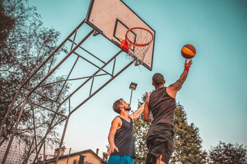 Two friends jump at basketball.