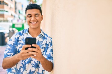 Fototapeta premium Young arab tourist man wearing summer style using smartphone leaning on the wall at street of city.