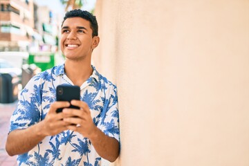 Fototapeta premium Young arab tourist man wearing summer style using smartphone leaning on the wall at street of city.