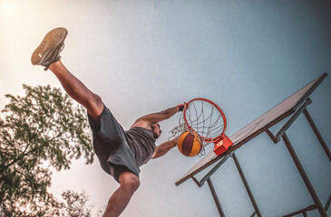 Basketball street player makes a dunk. It is played outdoors.