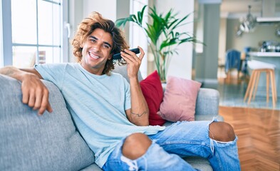 Young hispanic man smiling happy talking on the smartphone at home