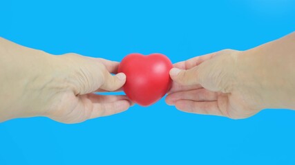 Hands holding red heart against blue background, health, medicine and charity concept
