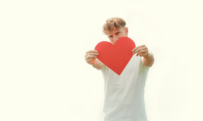 young happy casual man holding a big red heart for valentine's day on white background
